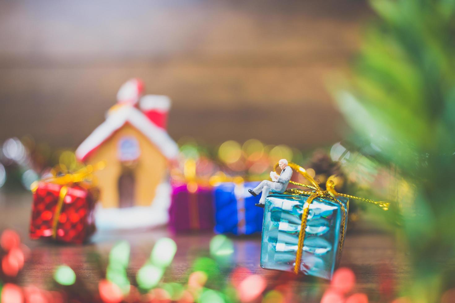 Persona en miniatura en una caja de regalo con decoración de celebración navideña en el fondo foto