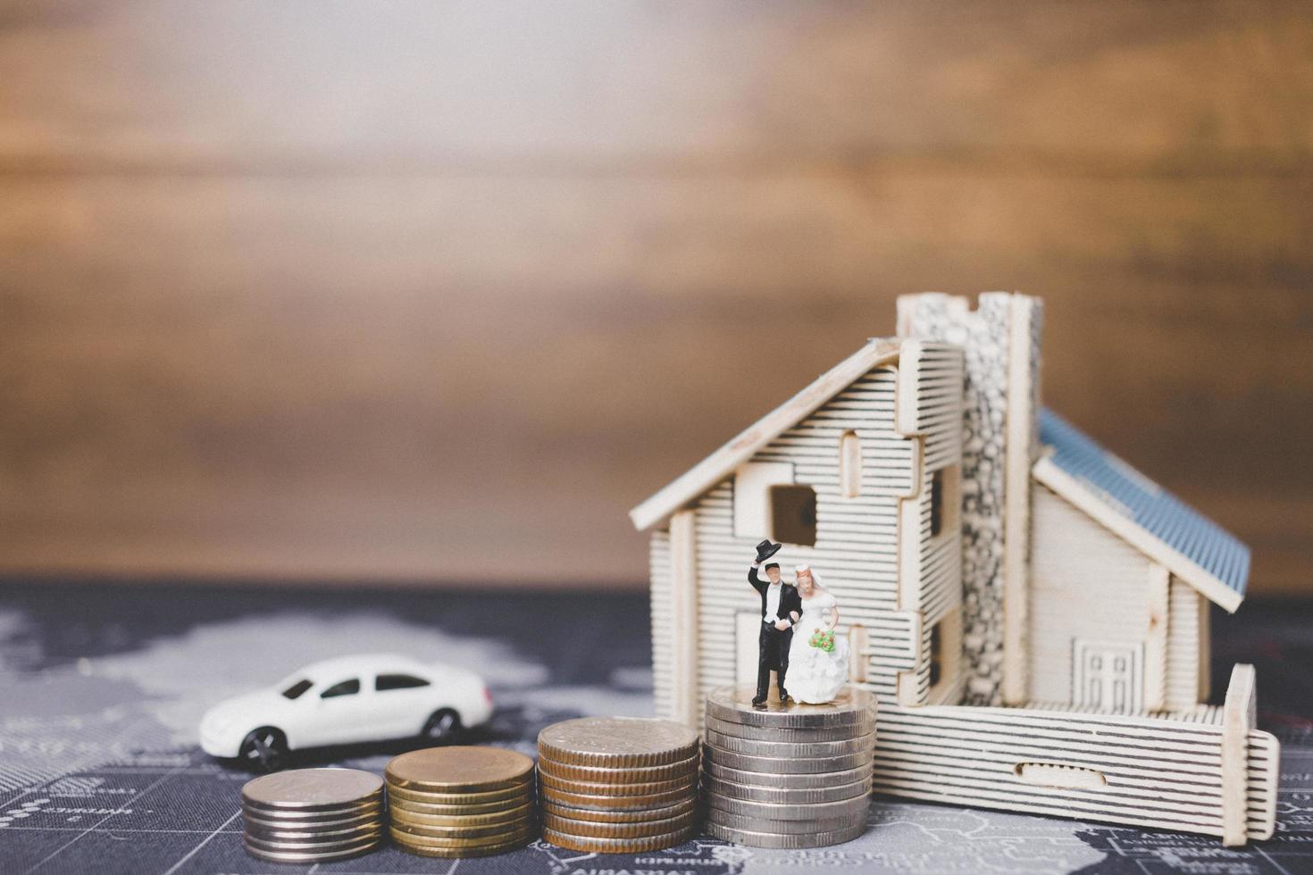 Miniature bride and groom with coins in front of a home, successful family concept photo