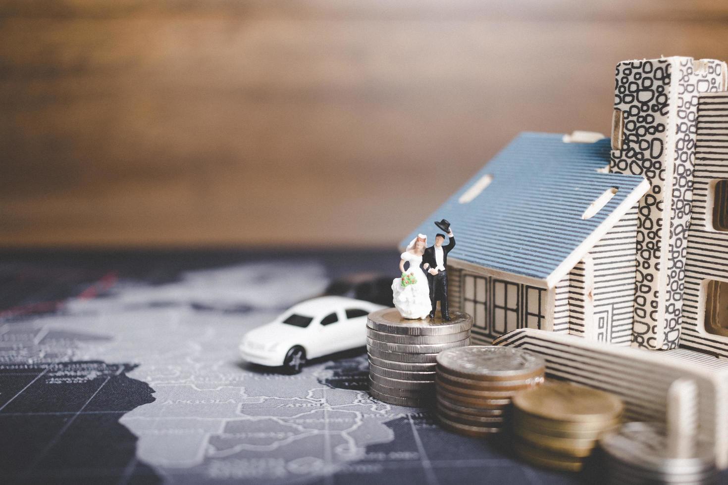 Miniature bride and groom with coins in front of a home, successful family concept photo