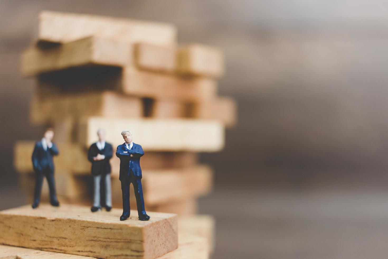 Miniature businessmen standing on a wooden block photo