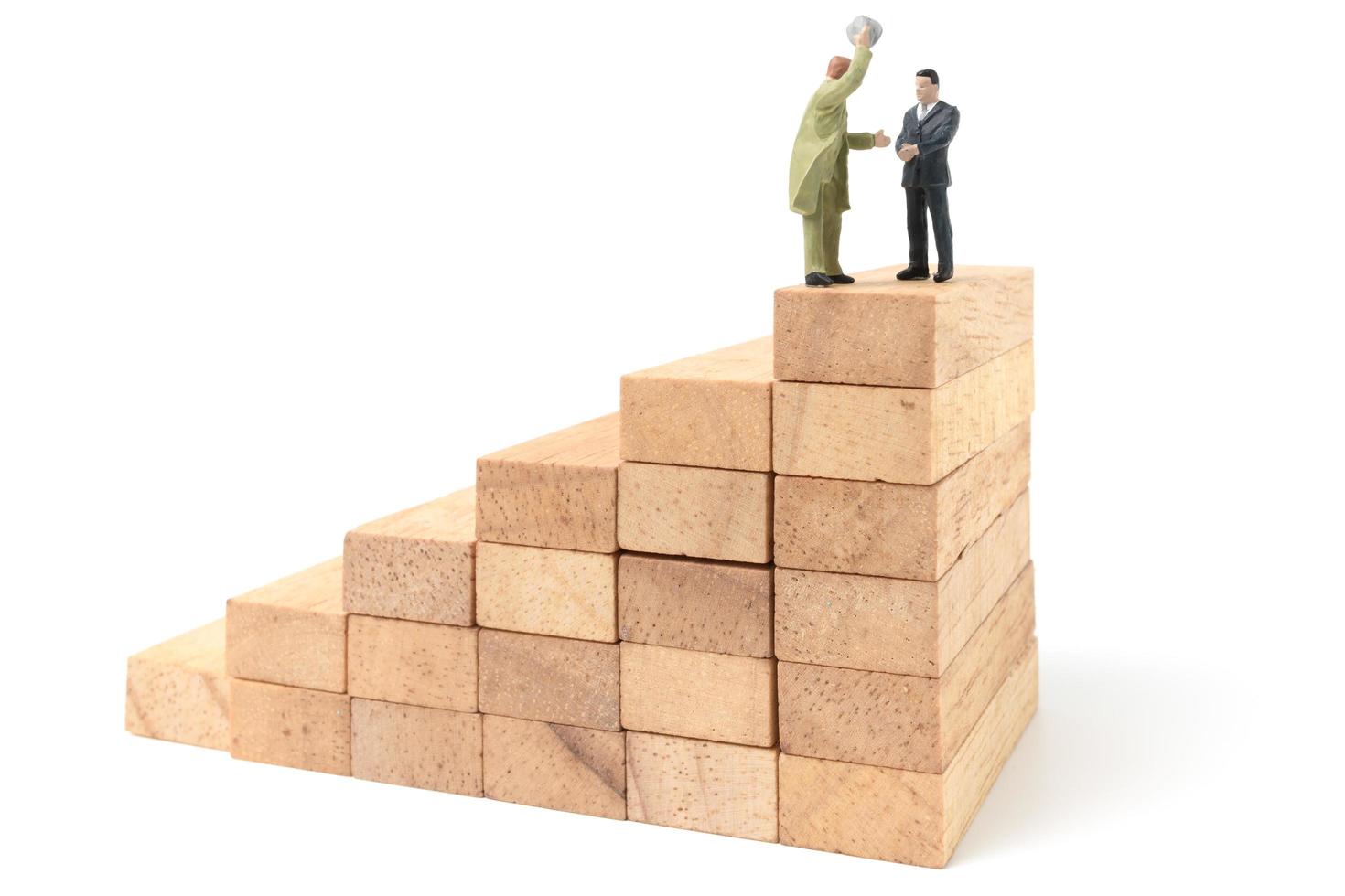Miniature businesspeople standing on wood blocks isolated on a white background photo