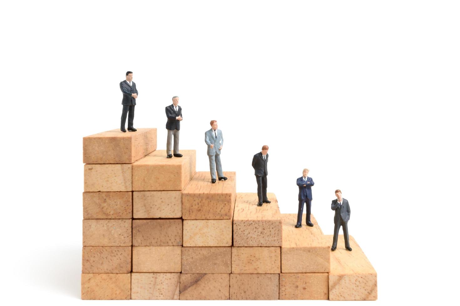 Miniature businesspeople standing on wood blocks isolated on a white background photo