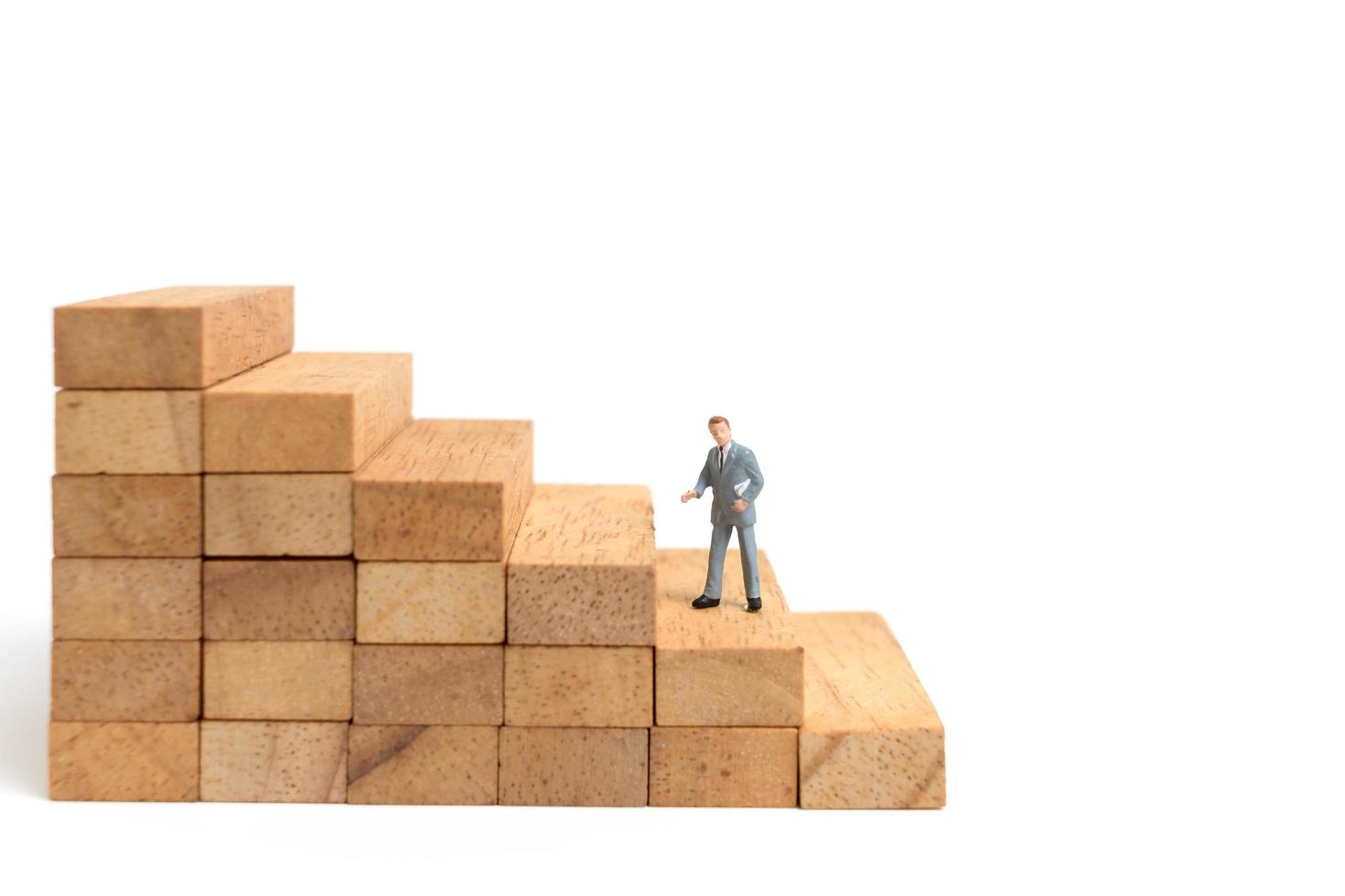 Miniature businesspeople standing on wood blocks isolated on a white background photo