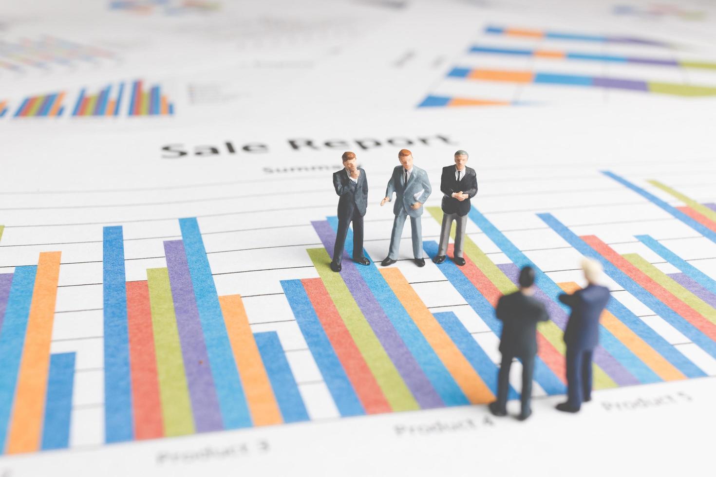 Miniature businessmen standing on a paper graph chart, developing teamwork concept photo