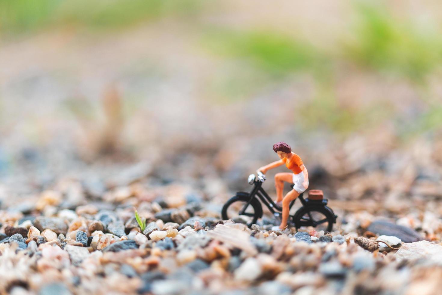 Viajero en miniatura en bicicleta, explorando el concepto del mundo. foto