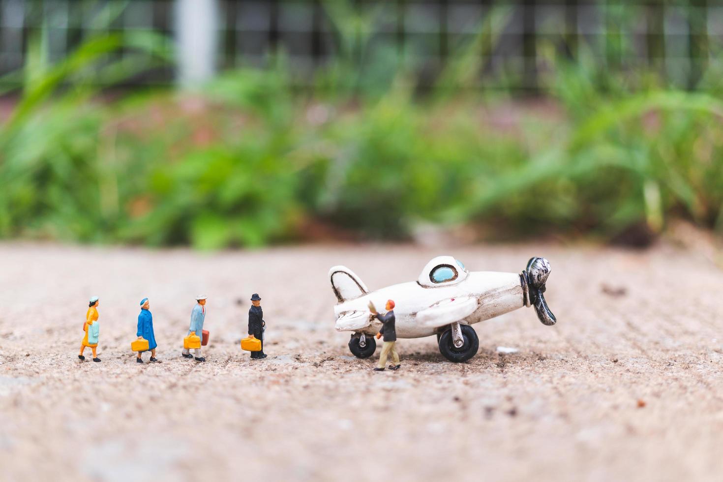 Miniature travelers holding carry-on luggage getting on a plane, exploring the world concept photo