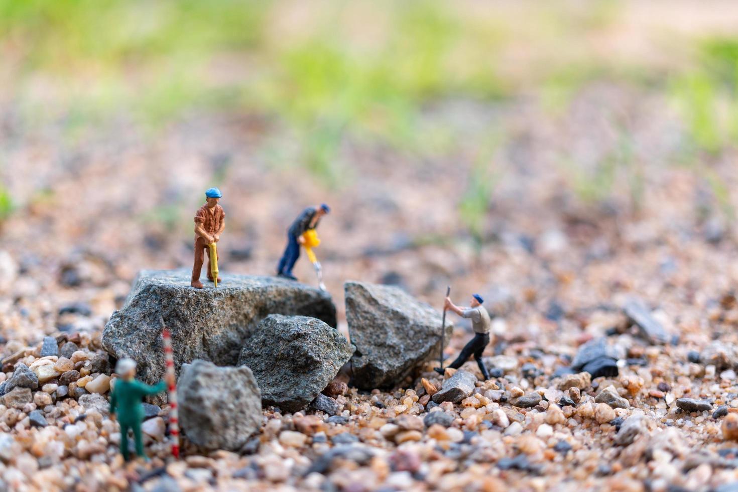 Miniature workers on a rock, teamwork concept photo