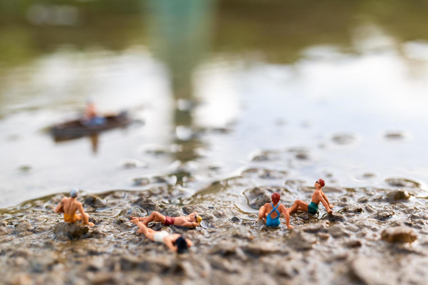 Gente en miniatura vistiendo trajes de baño relajándose en una playa, concepto de verano foto