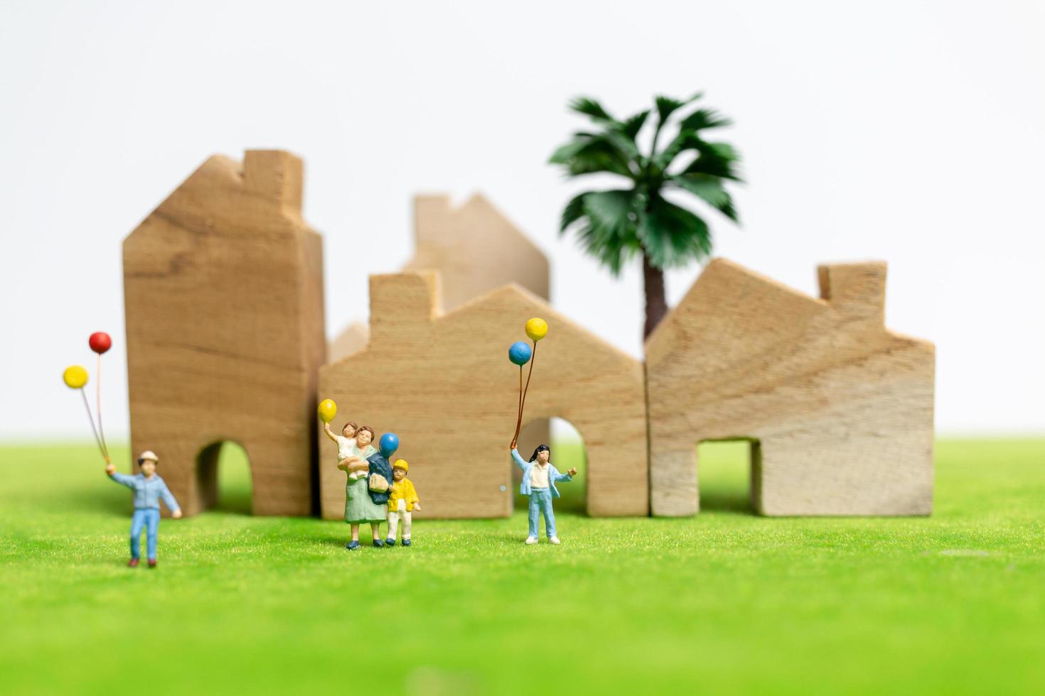 Familia en miniatura caminando en un campo con globos, concepto de tiempo en familia feliz foto