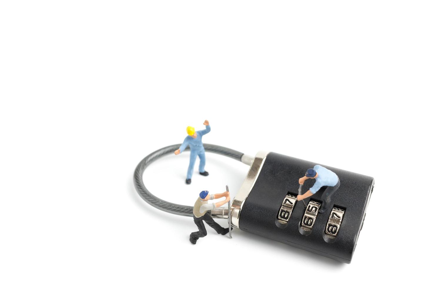 Miniature workers unlocking the password on a lock, teamwork concept photo