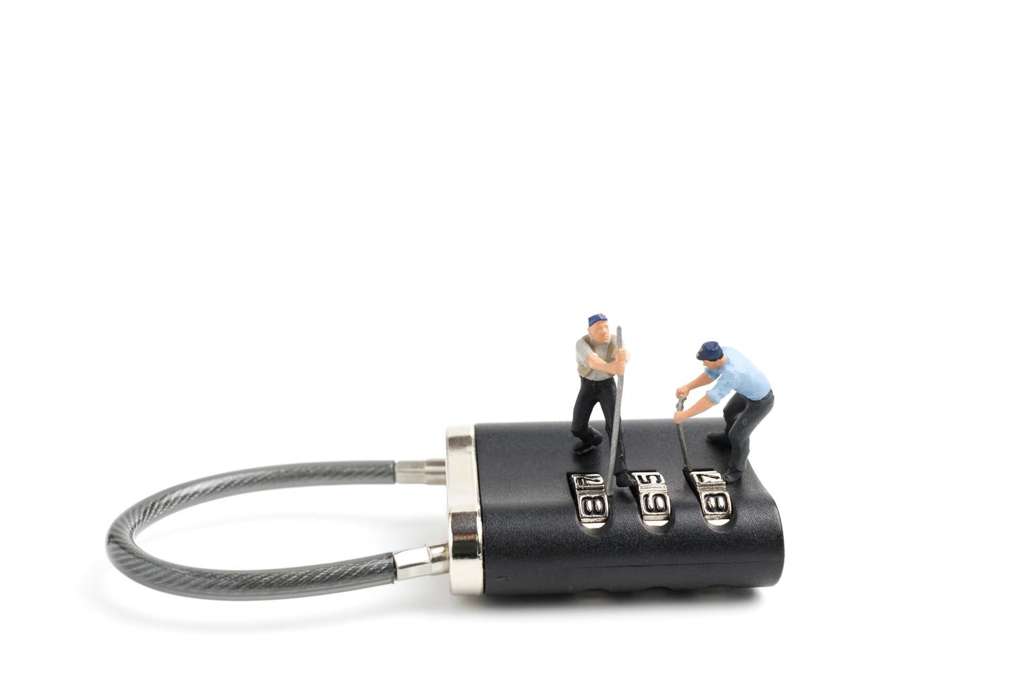 Miniature workers unlocking the password on a lock, teamwork concept photo