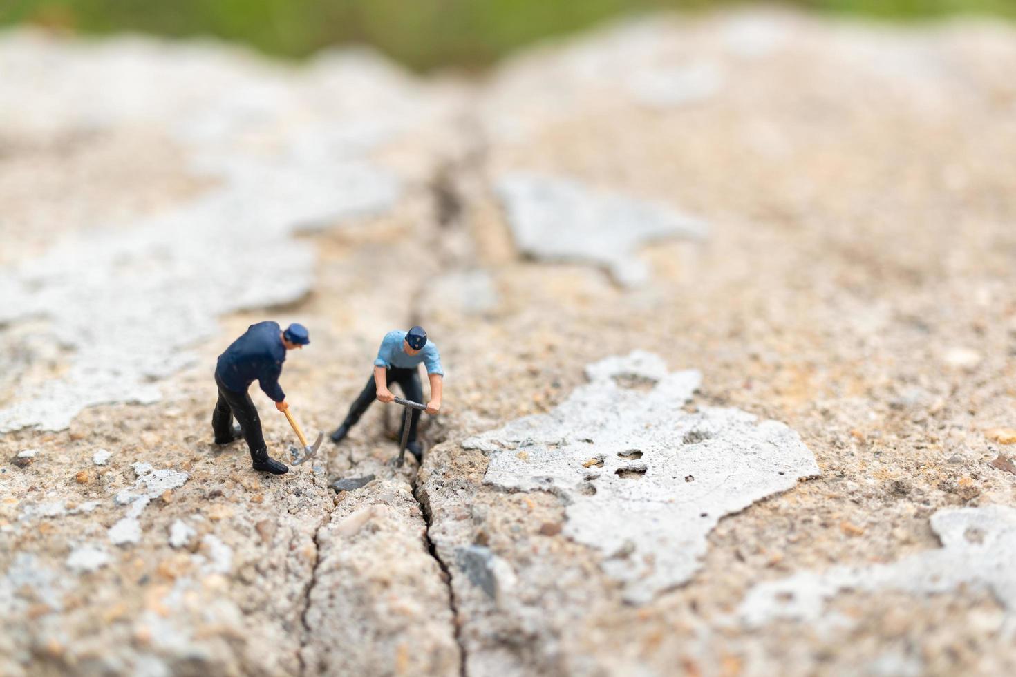 Trabajadores en miniatura que trabajan en hormigón con grietas, concepto de trabajo en equipo foto