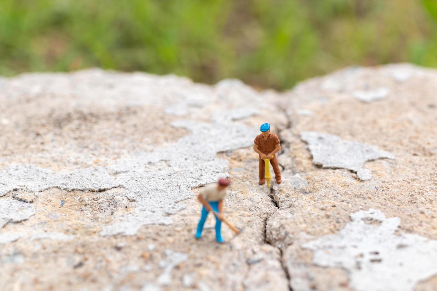 Trabajadores en miniatura que trabajan en hormigón con grietas, concepto de trabajo en equipo foto