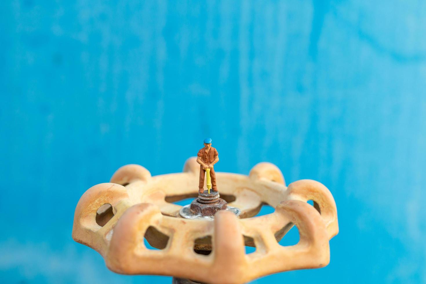 Plomero en miniatura instalando tuberías de agua y comprobando daños en una máquina bomba de agua foto