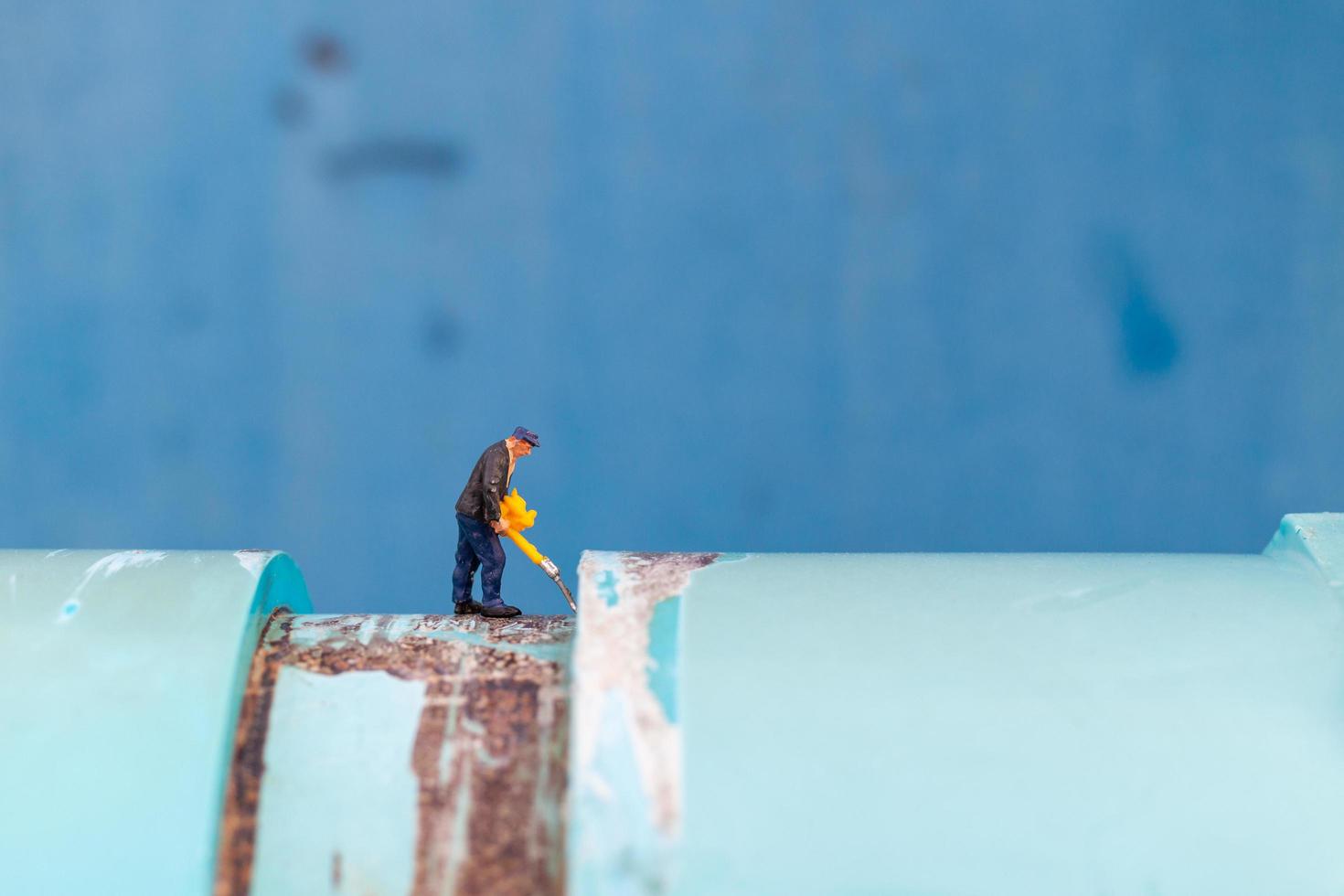 Miniature plumber installing water pipes and checking damage on a water pump machine photo