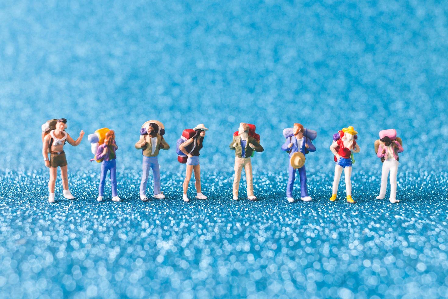 Miniature backpackers, tourist people on a blue glitter background photo