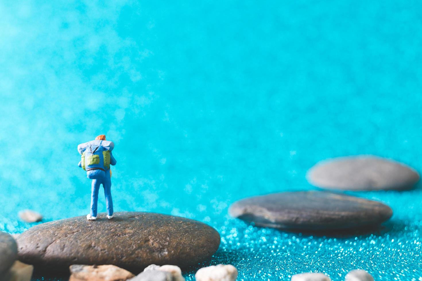 Mochilero en miniatura, gente turística sobre un fondo azul brillante foto