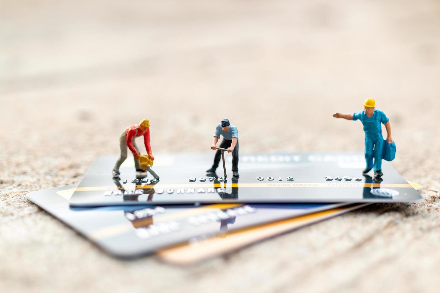 Miniature workers working on a credit card, business and finance concept photo