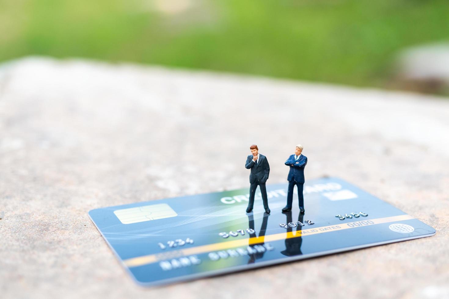 Miniature businesspeople standing on a credit card, business and finance concepts photo