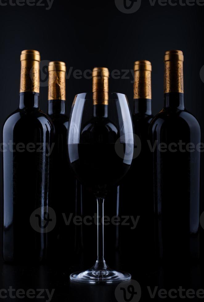 botellas de vino y vidrio con fondo negro foto
