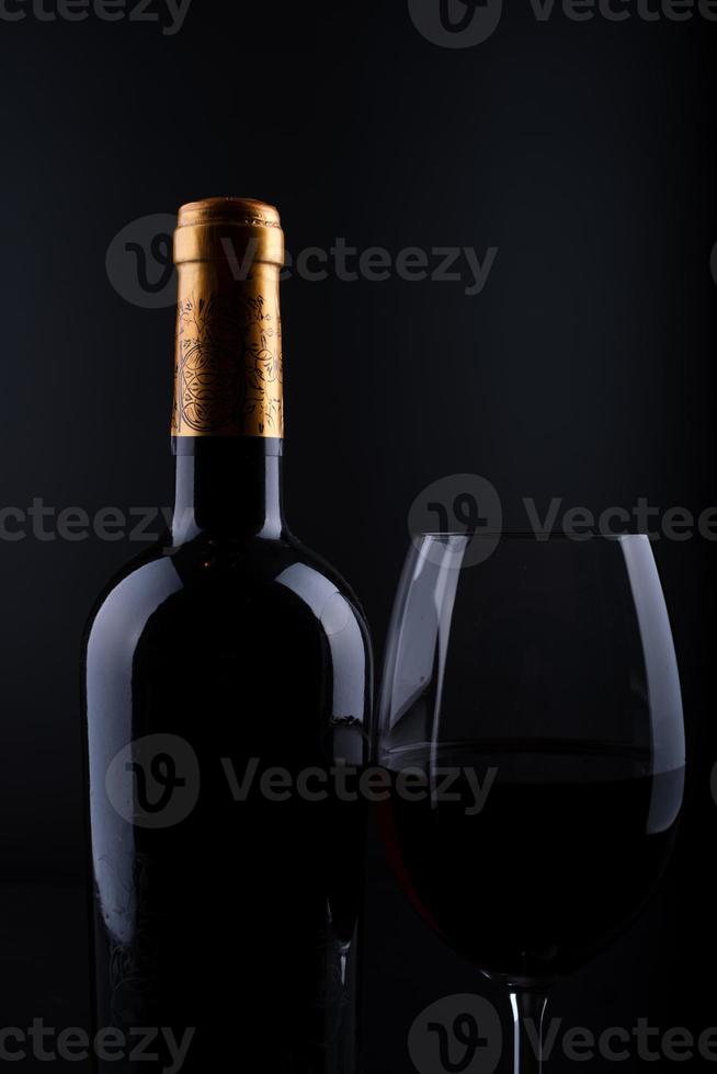 Closeup botella de vino y vidrio con fondo negro foto