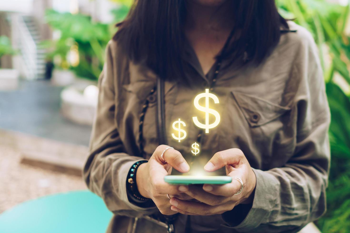 mujer usa un teléfono inteligente para ganar dinero en línea con el icono de dólar emergente foto