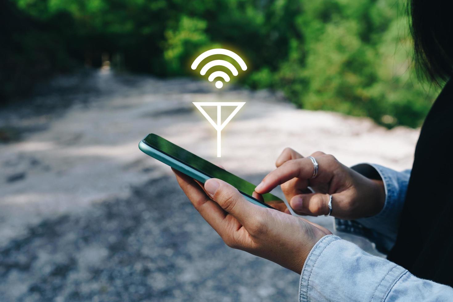 La mano de la persona con un teléfono inteligente en busca de señal wifi en el bosque foto