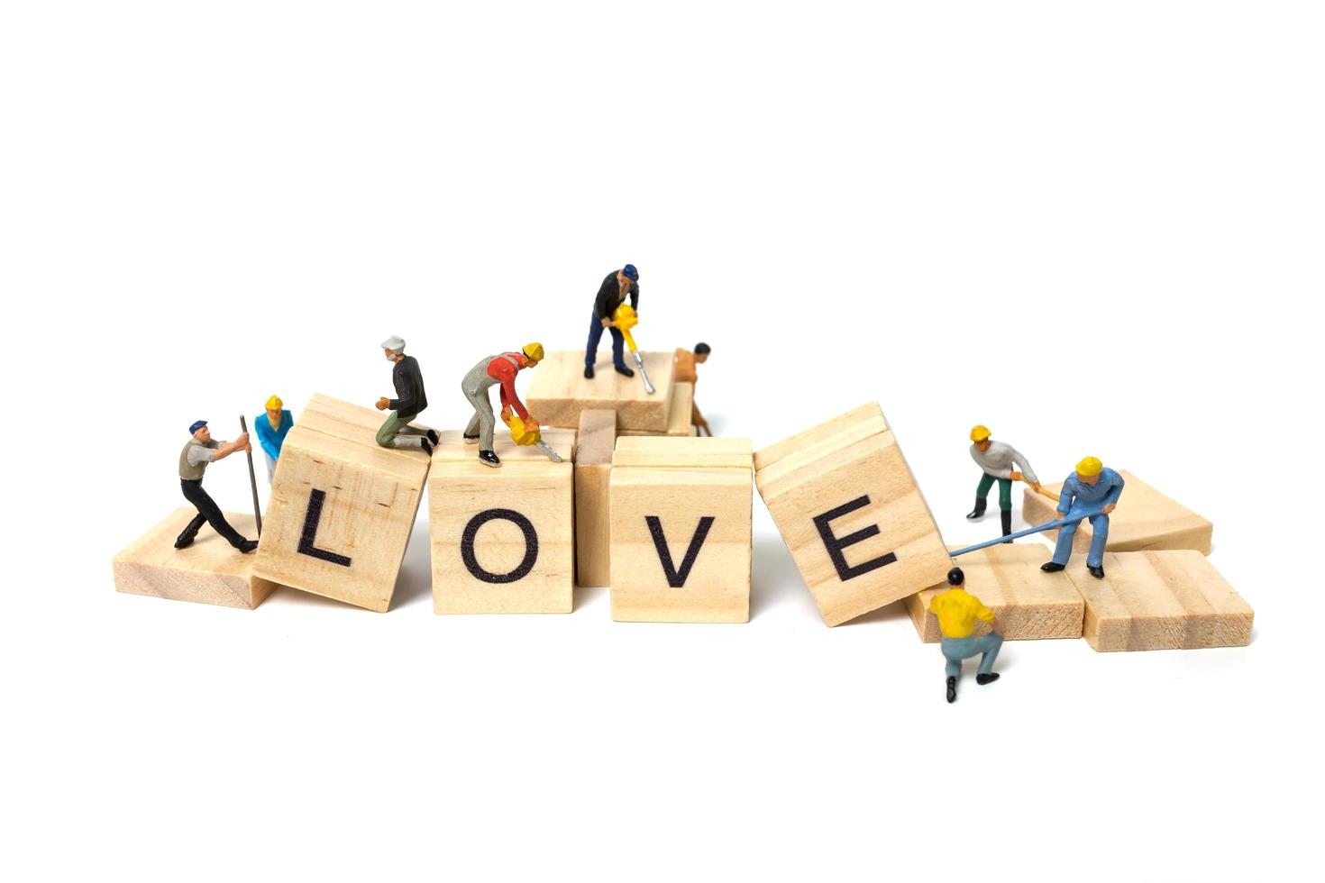 Trabajadores en miniatura construyendo la palabra amor en bloques de madera con un fondo blanco, el concepto del día de San Valentín foto