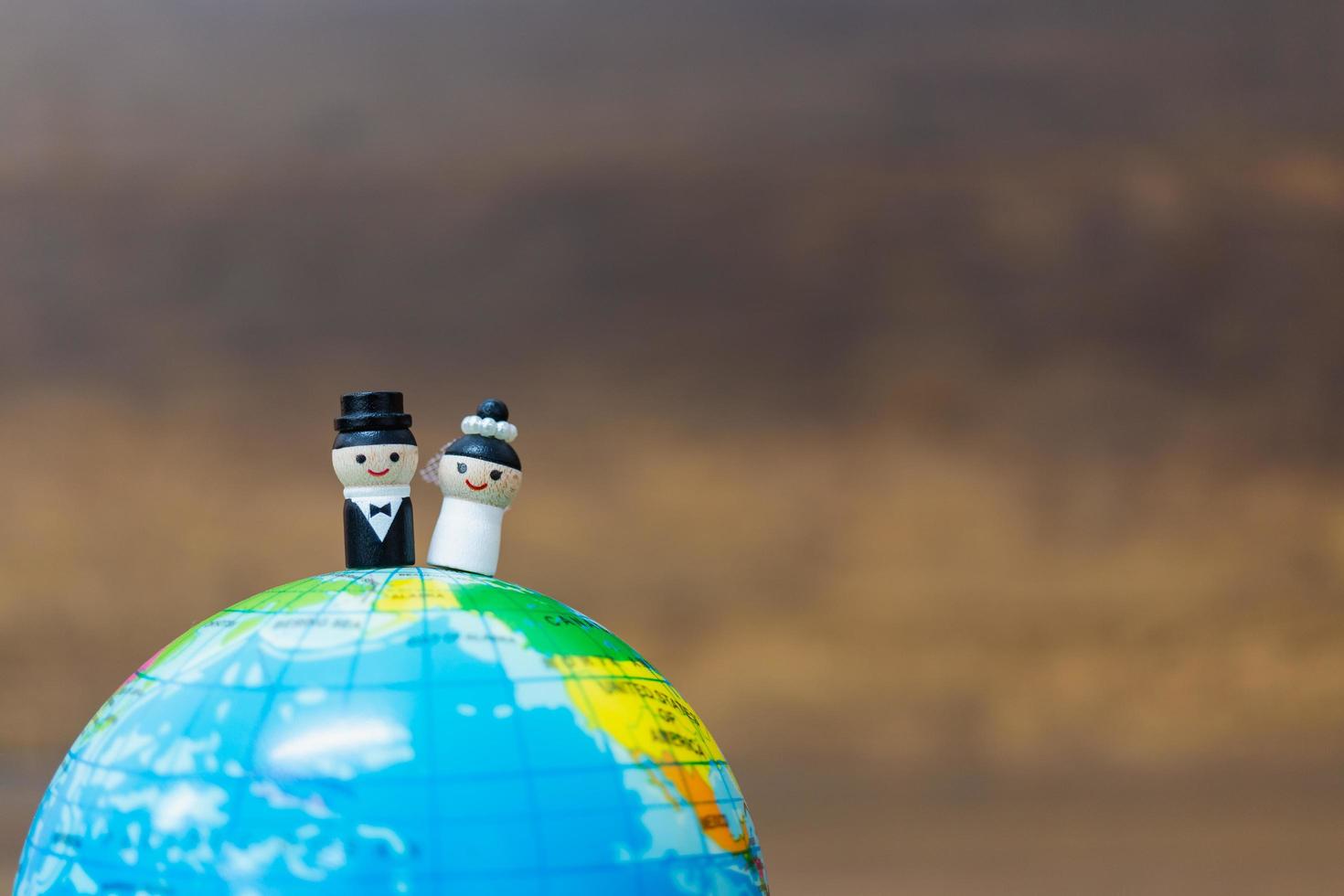 Muñecas de madera en miniatura en un globo terráqueo con un fondo de madera foto