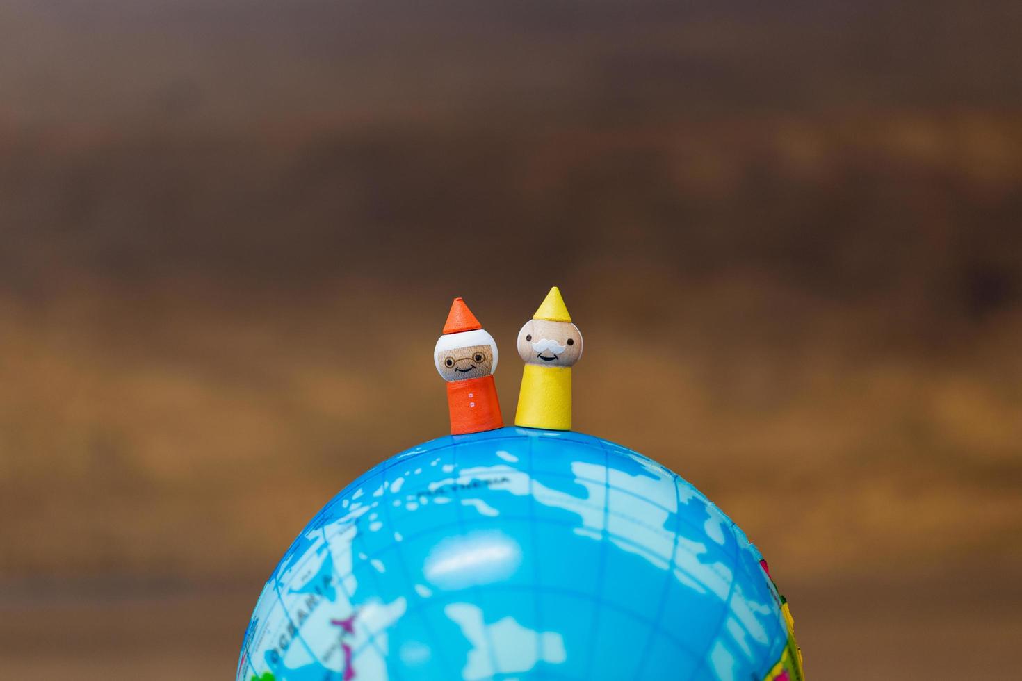 Muñecas de madera en miniatura en un globo terráqueo con un fondo de madera foto