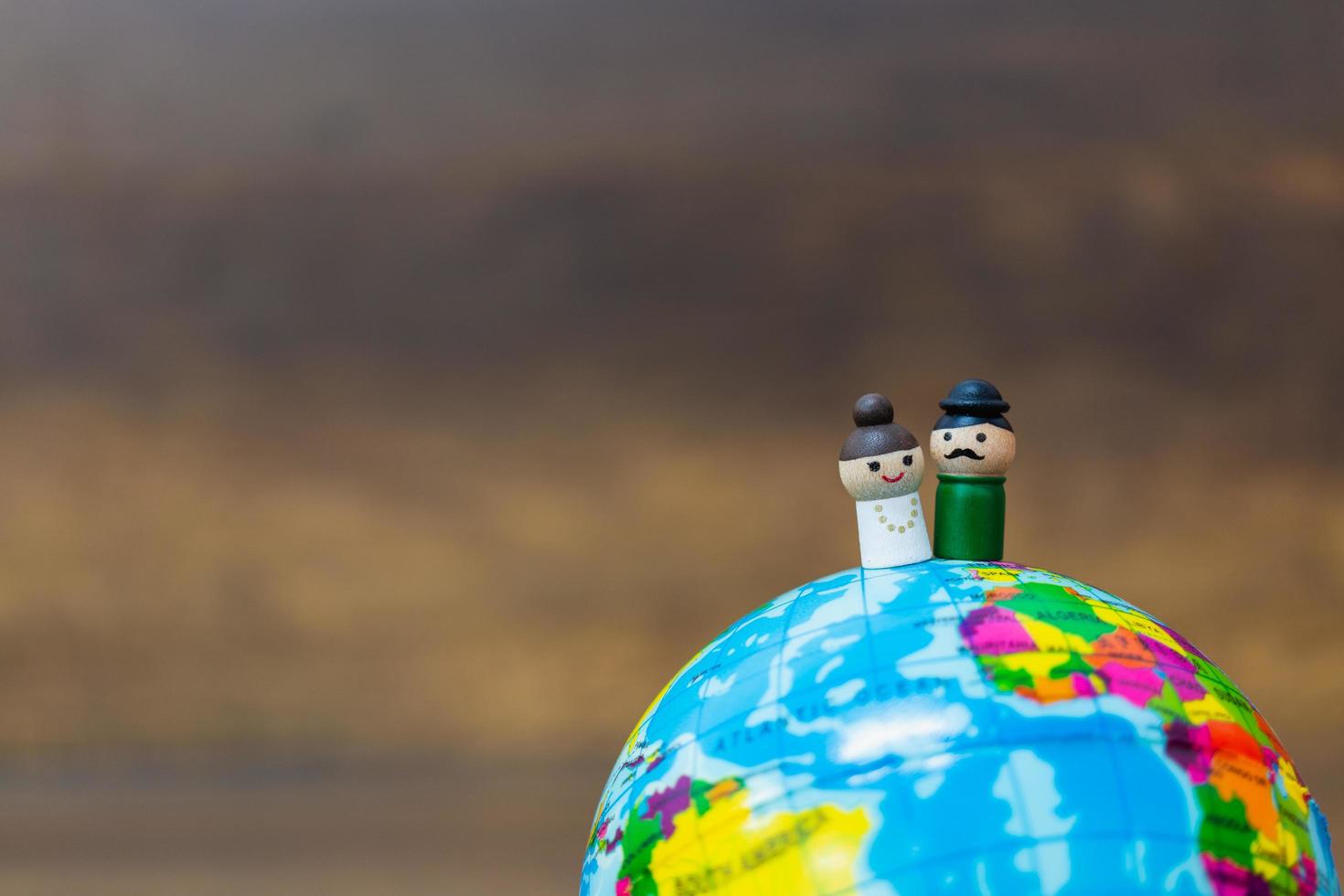 Muñecas de madera en miniatura en un globo terráqueo con un fondo de madera foto