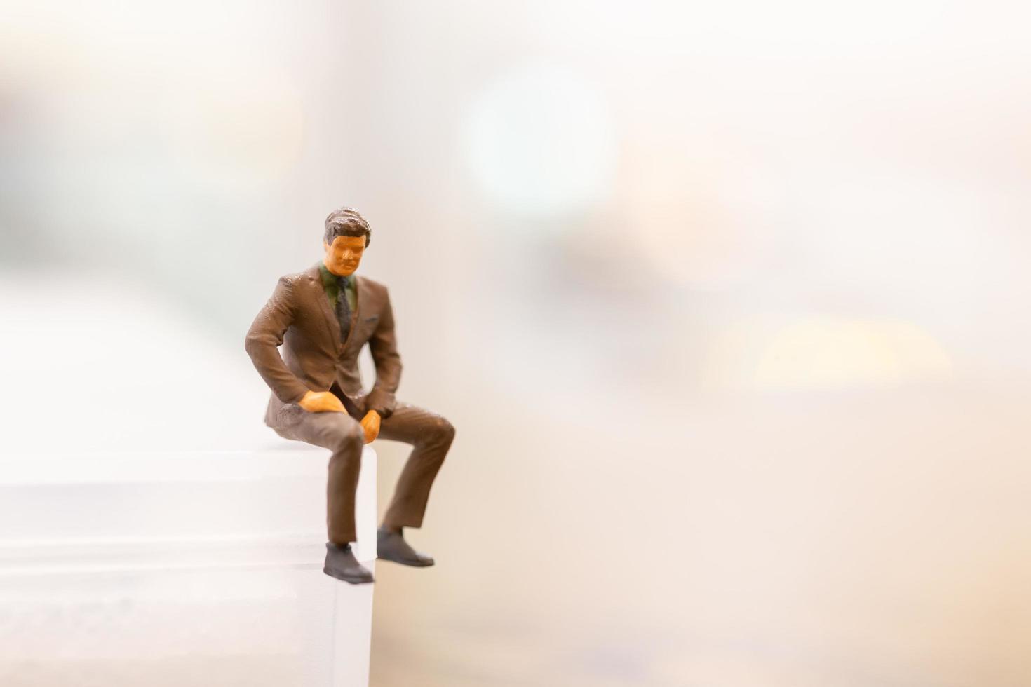 Miniature businessman sitting on empty space photo