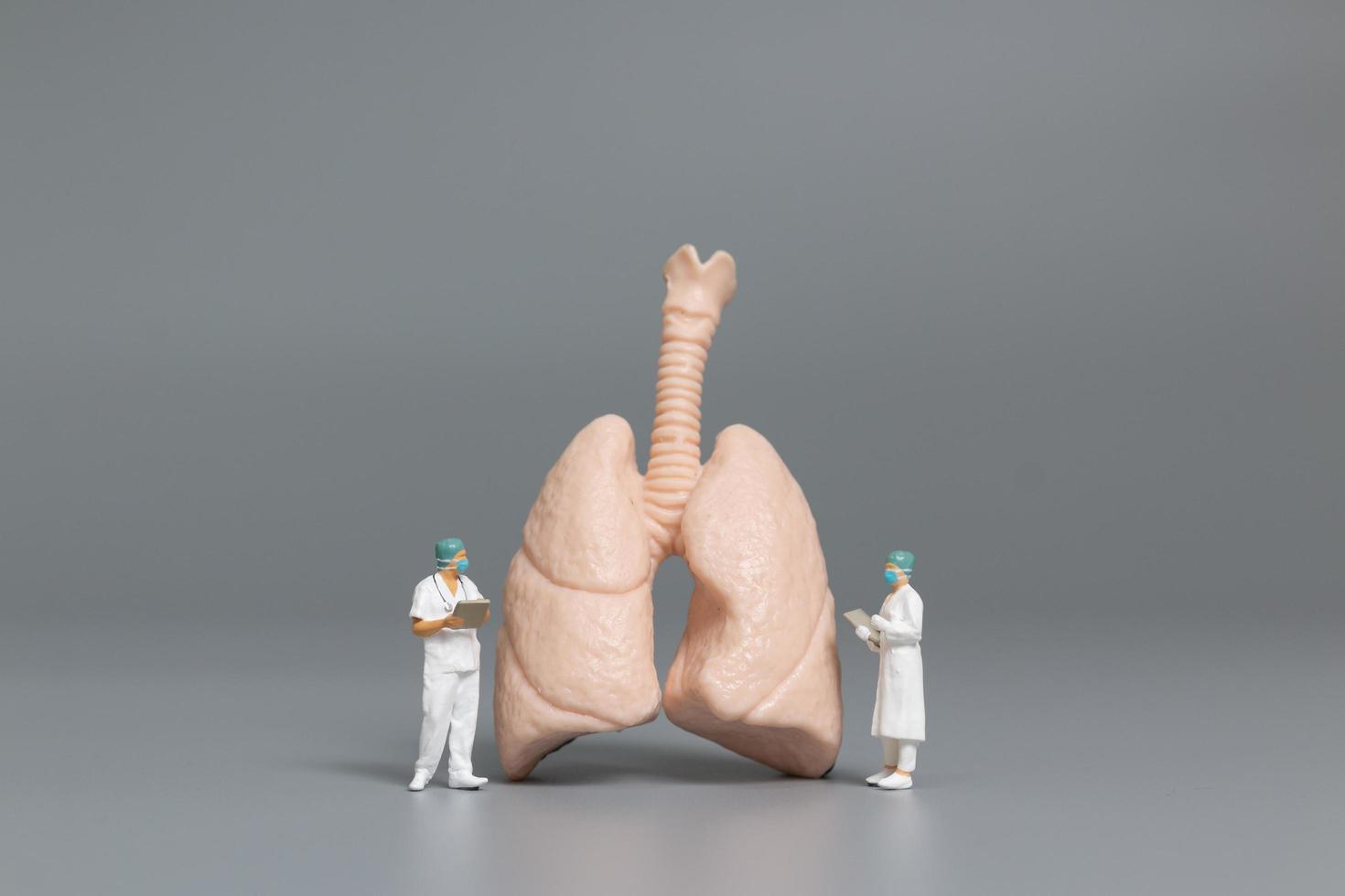 Miniature doctors and nurses observing and discussing the human lung, virus and bacteria-infected concept photo
