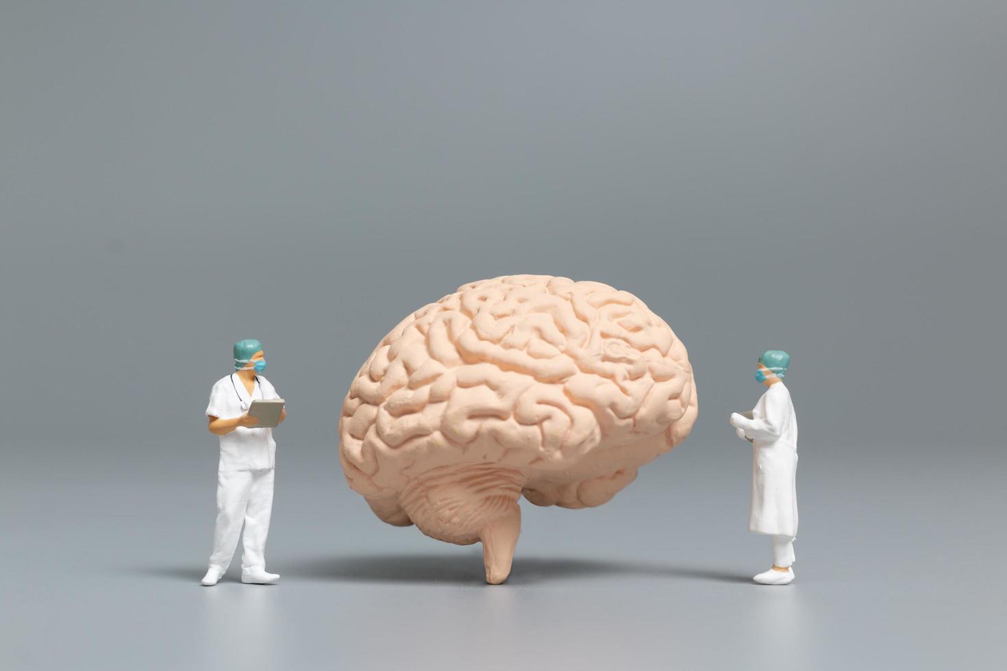 Médico y enfermera en miniatura observando y discutiendo el cerebro humano, la ciencia y el concepto médico. foto