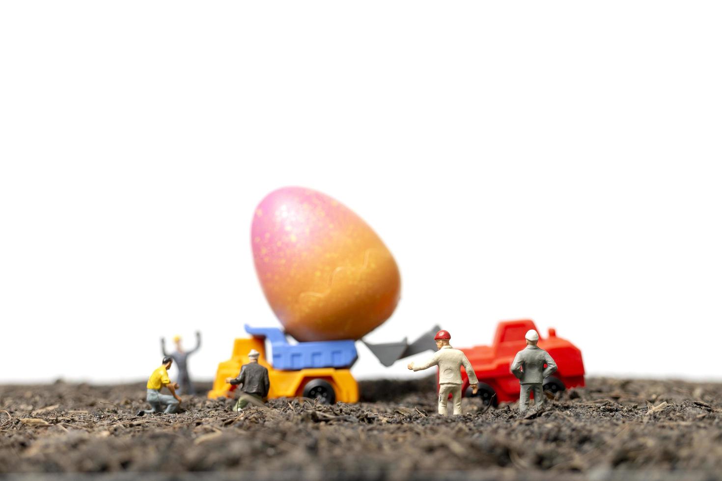 Gente en miniatura trabajando en huevos de pascua para el día de pascua con un fondo blanco. foto