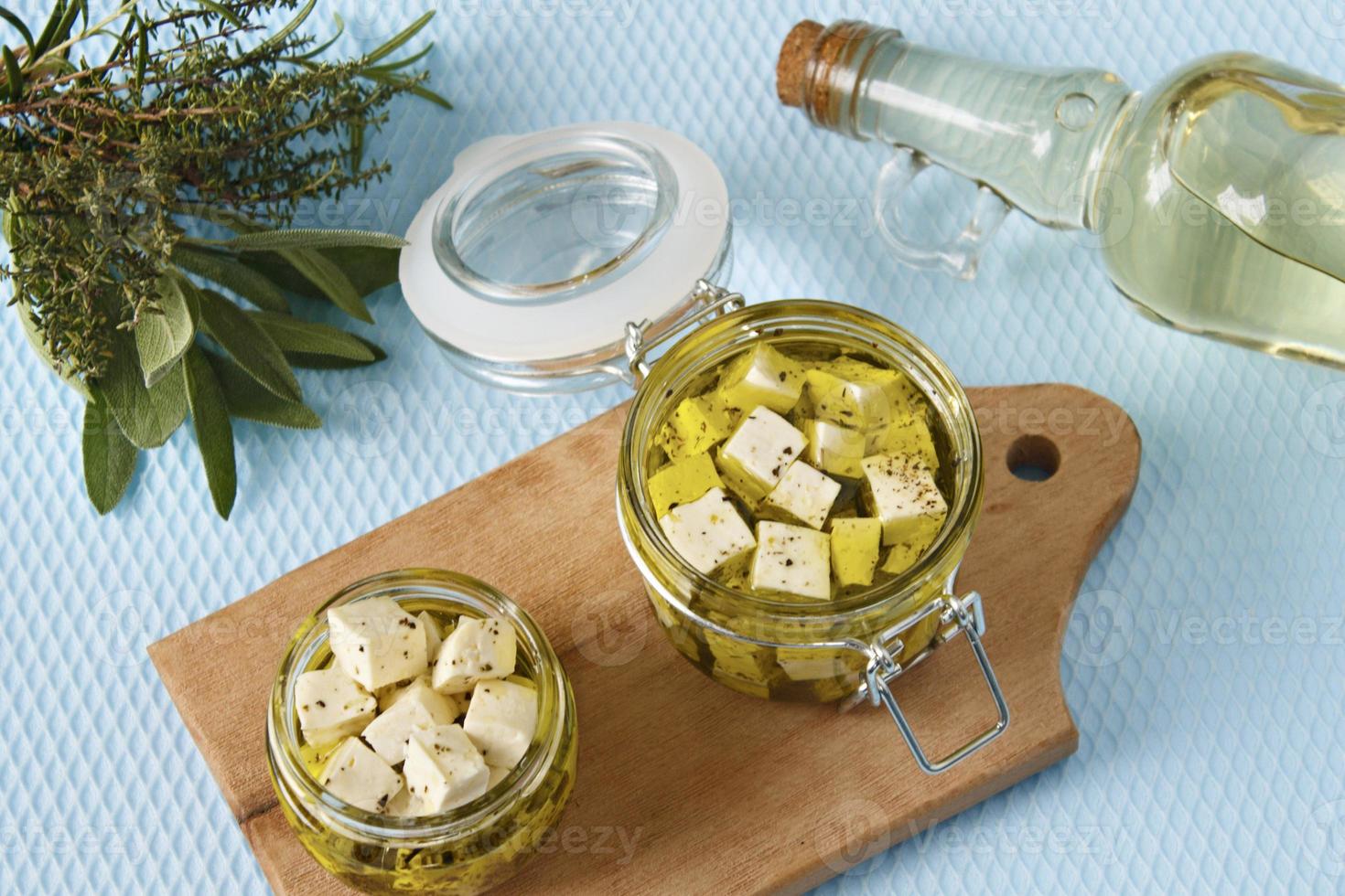 Marinated feta in a glass jar and spices against a blue background photo