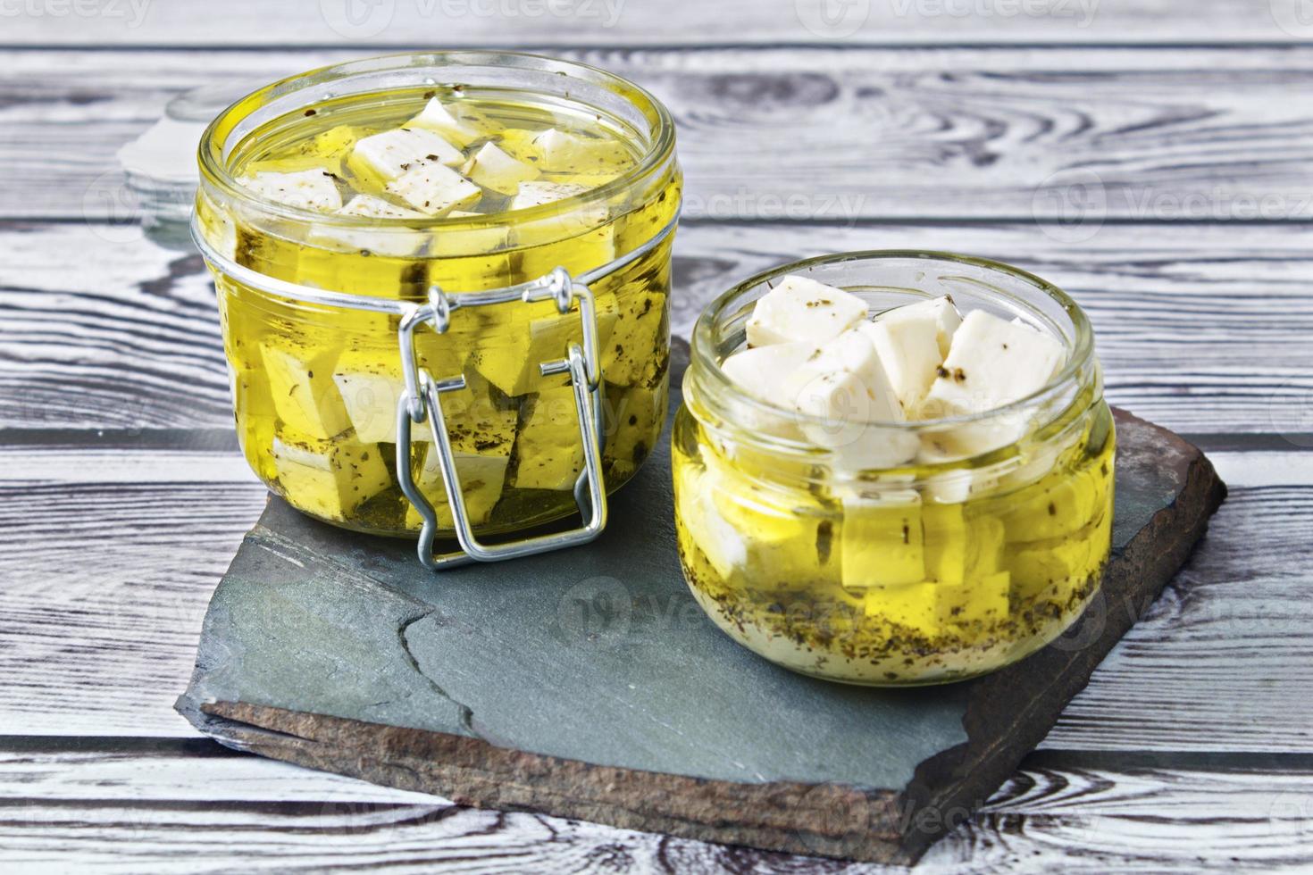 Marinated feta in a glass bath on a wooden background photo