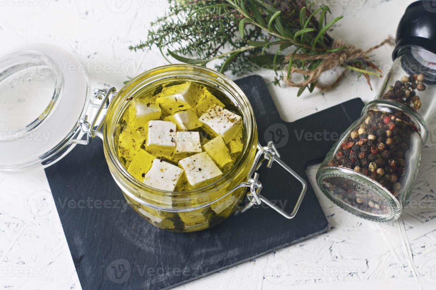 Marinated feta in a glass jar and spices against a white background photo