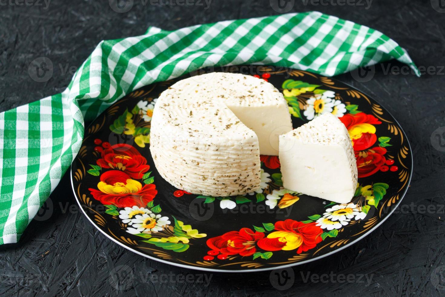 Queso blanco en un plato sobre un fondo negro y servilleta foto