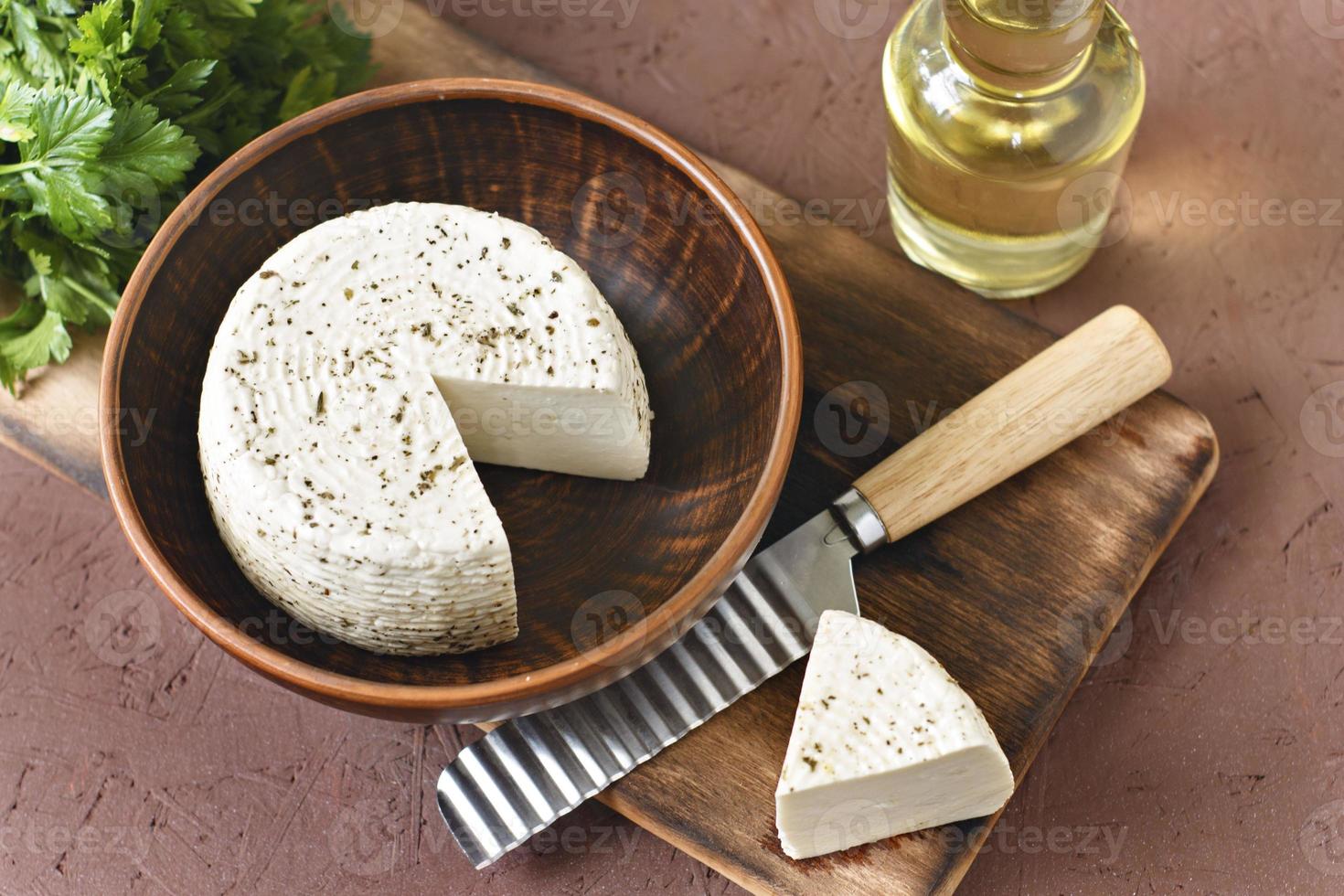 Queso blanco sobre una tabla de madera con aceite de oliva sobre un fondo marrón foto