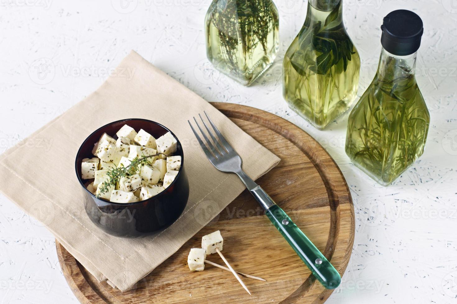 Queso blanco sobre una tabla de madera con aceite de oliva sobre un fondo blanco. foto