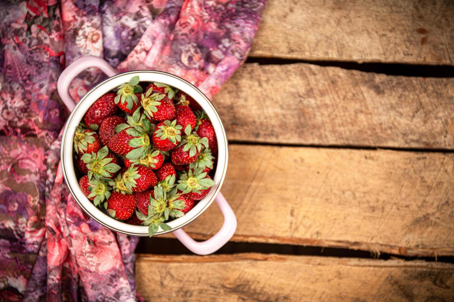 Strawberries in a bucket bowl on a wooden surface photo