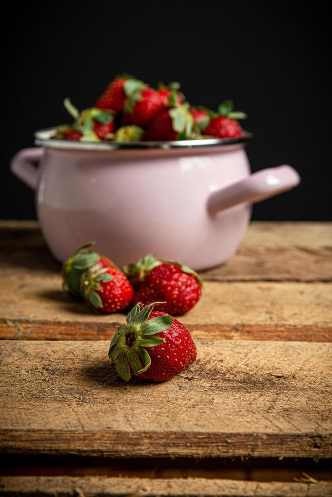 Fresas en un recipiente sobre una mesa de madera foto