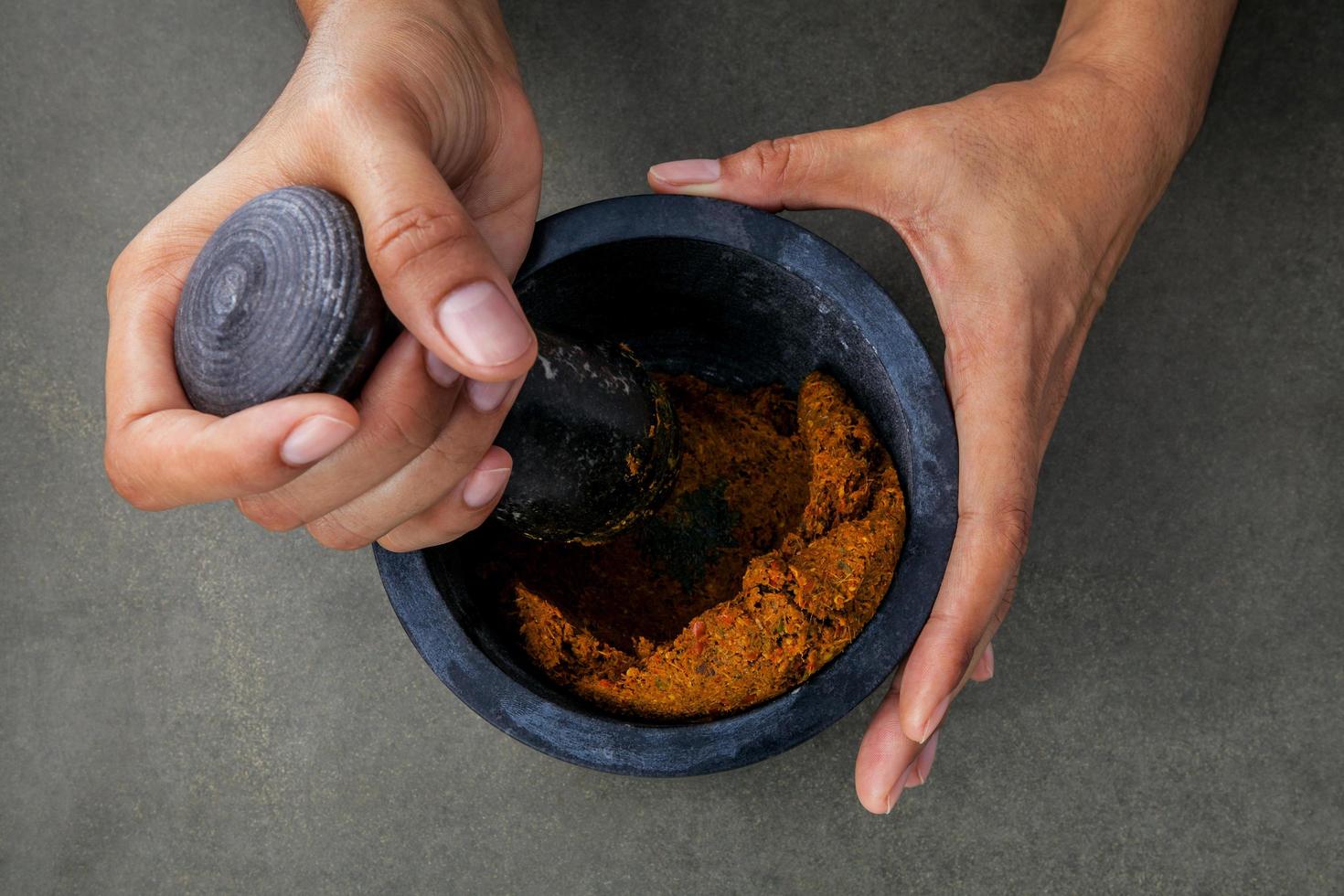 Top view of a person grinding spices in a mortar photo