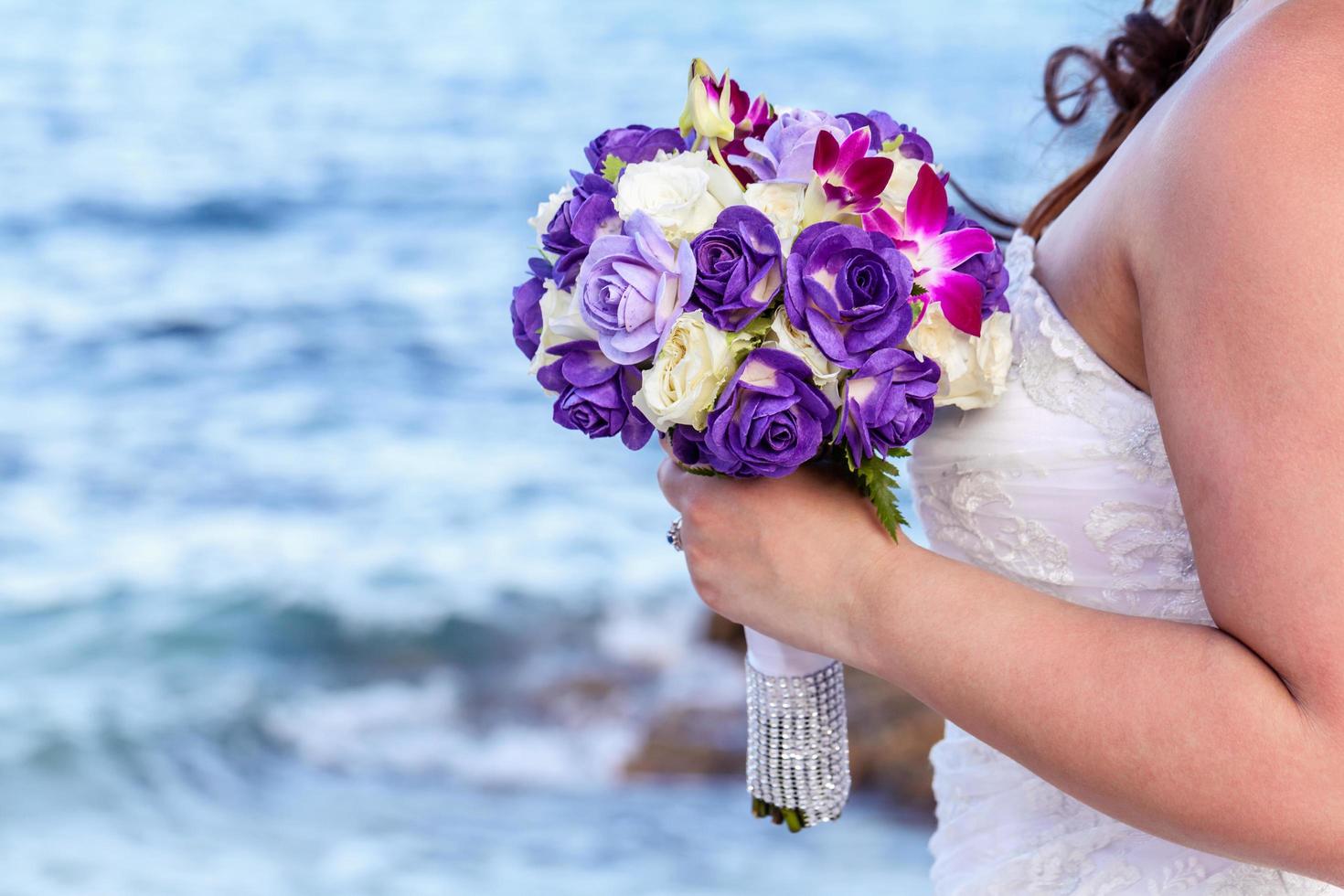 novia sosteniendo ramo de novia en una playa tropical foto