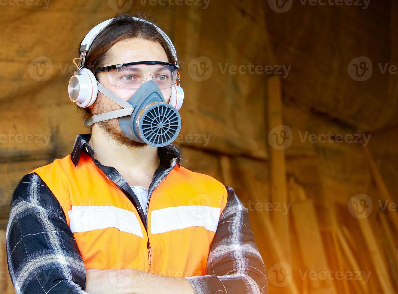 Portrait of a young carpenter wearing safety gloves and soundproof earmuffs photo