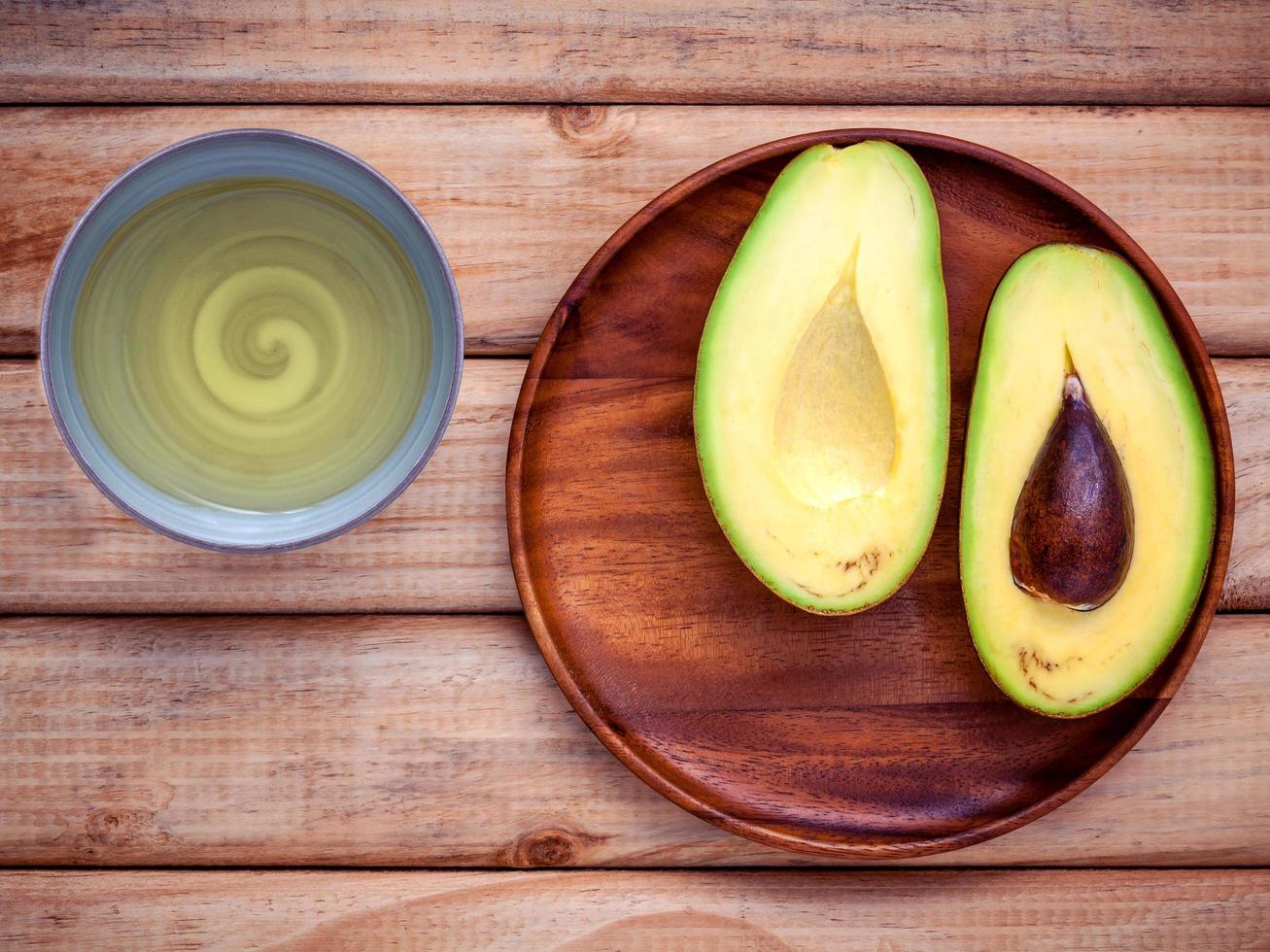 Aguacate fresco en una placa de madera con aceite de aguacate foto