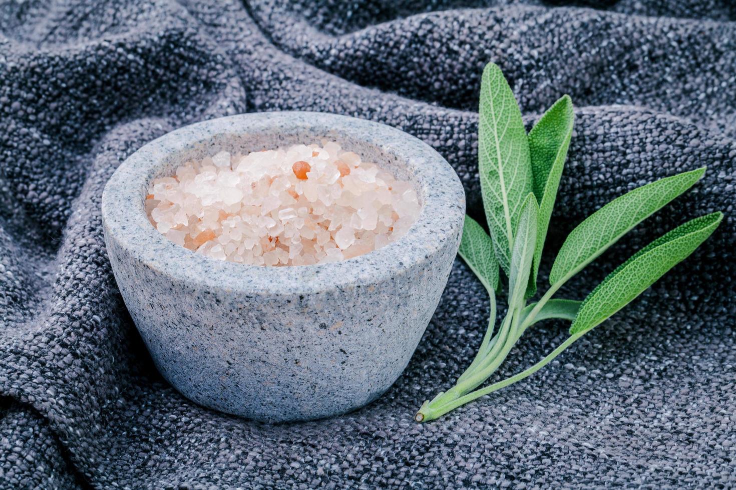Himalayan pink salt in a white mortar with sage leaves photo