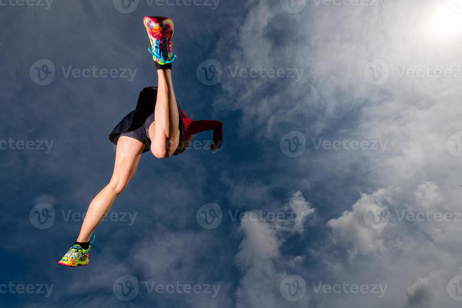 Athletic girl jumps while running in the mountains photo