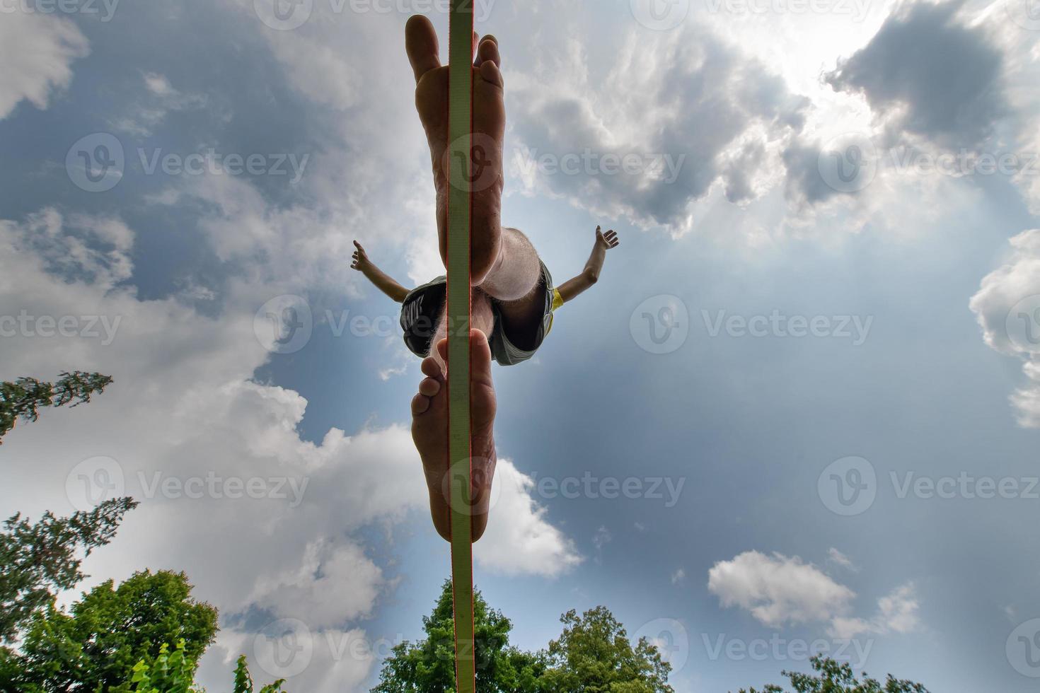 A barefoot young man walking on a webbing in balance photo